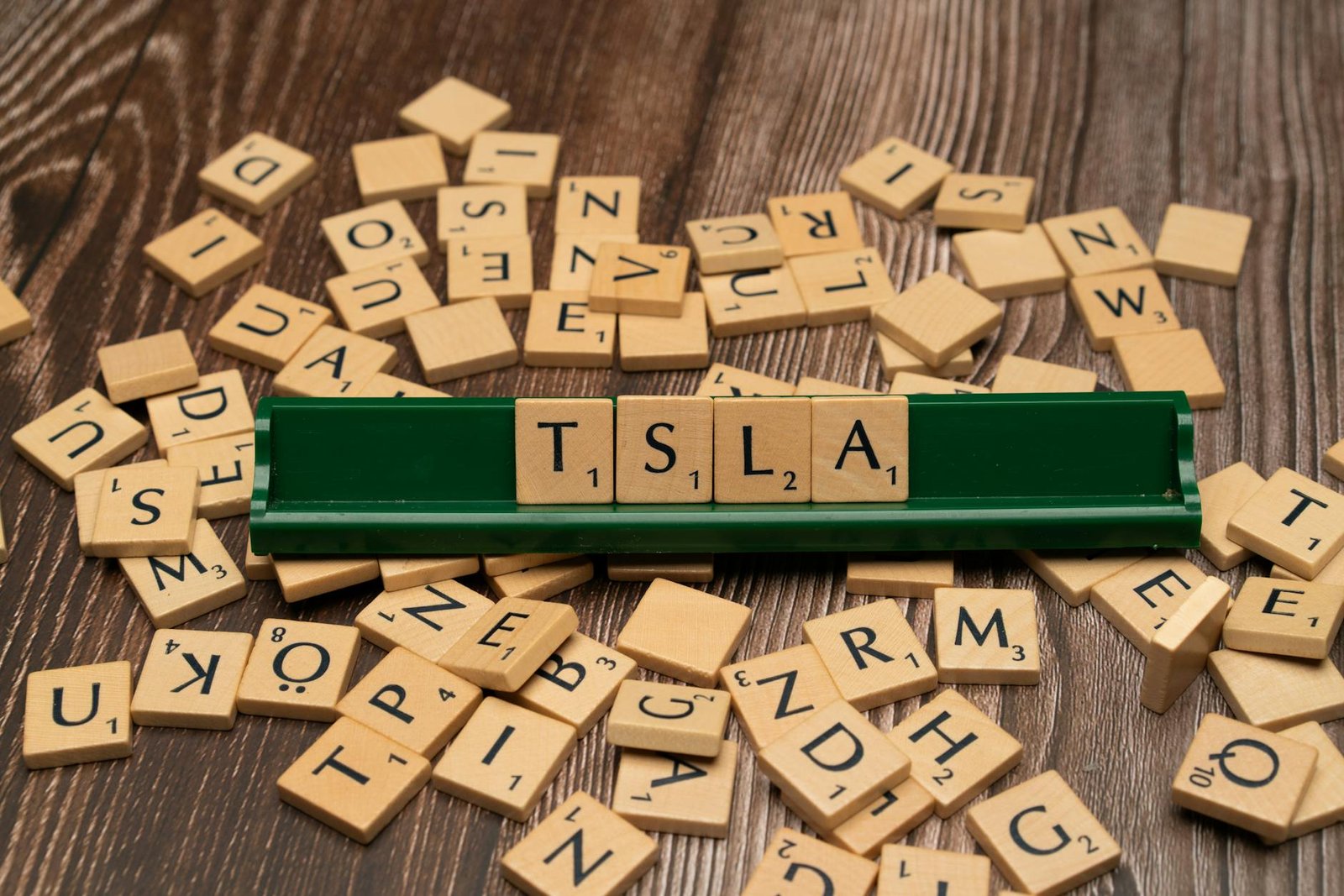 Scrabble tiles spell "TSLA," symbolizing stock market education and investment strategies.