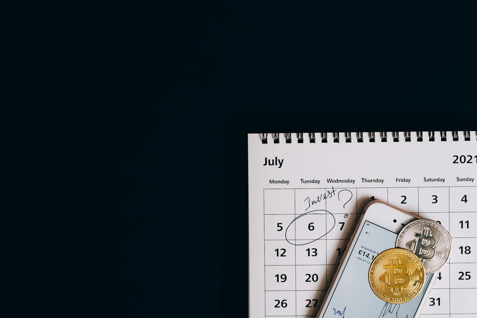 Calendar and smartphone with Bitcoin coins for effective trading plan management.